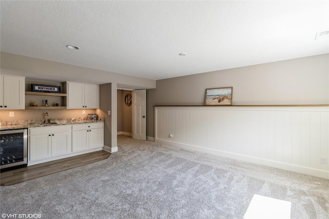 unfurnished living room featuring light carpet, wet bar, and wine cooler