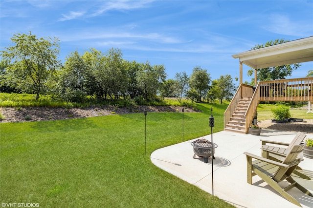 view of yard with a wooden deck, a fire pit, and a patio