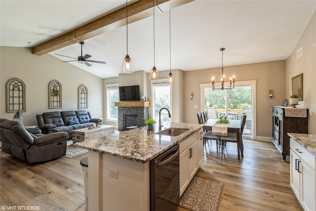 kitchen with sink, black dishwasher, white cabinetry, a kitchen island with sink, and light stone countertops