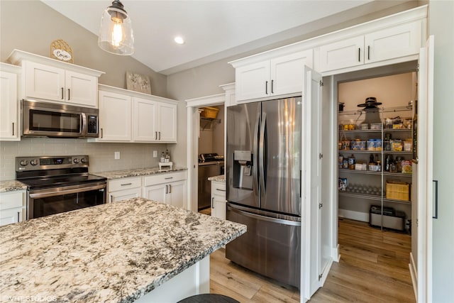 kitchen with appliances with stainless steel finishes, white cabinetry, backsplash, hanging light fixtures, and vaulted ceiling