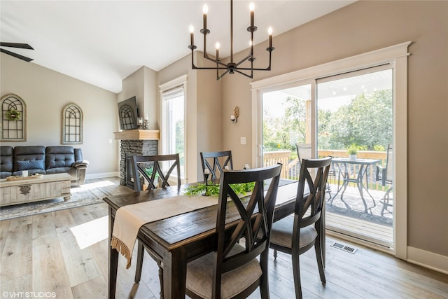 dining area with a fireplace, ceiling fan with notable chandelier, and light hardwood / wood-style floors