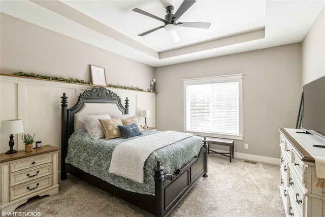 carpeted bedroom featuring a raised ceiling and ceiling fan