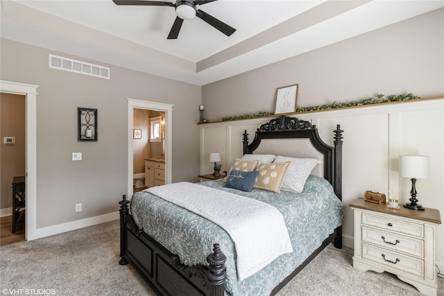 bedroom with ceiling fan, light carpet, and ensuite bath