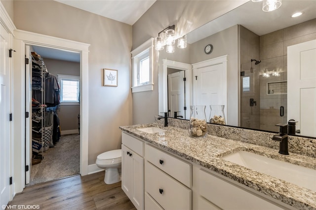 bathroom featuring hardwood / wood-style flooring, toilet, a shower with door, and vanity