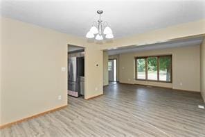 spare room with light wood-type flooring and a notable chandelier