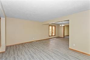 unfurnished room with a chandelier and light hardwood / wood-style floors