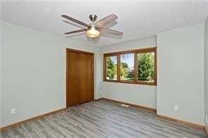 unfurnished bedroom with ceiling fan, a closet, and light hardwood / wood-style floors