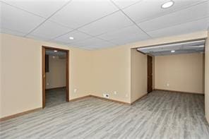 basement featuring a paneled ceiling and light wood-type flooring