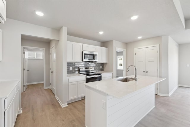 kitchen featuring sink, white cabinetry, tasteful backsplash, appliances with stainless steel finishes, and an island with sink