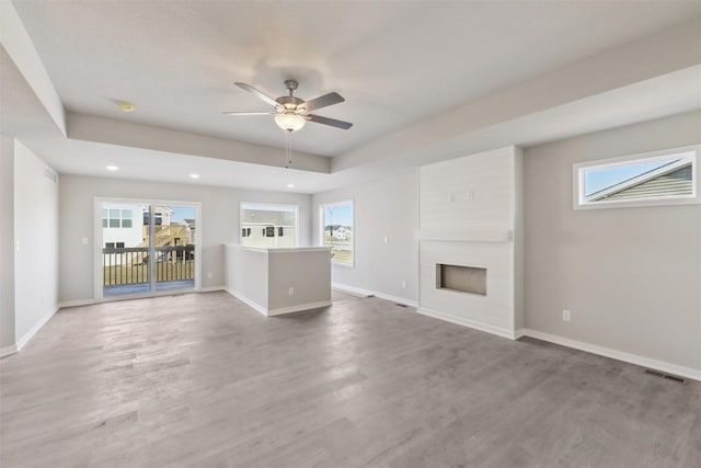 unfurnished living room with a fireplace, hardwood / wood-style flooring, plenty of natural light, and ceiling fan