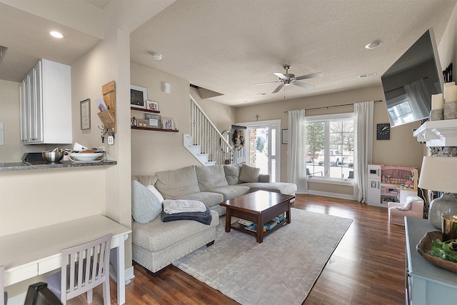 living room with ceiling fan, dark wood-type flooring, and a textured ceiling