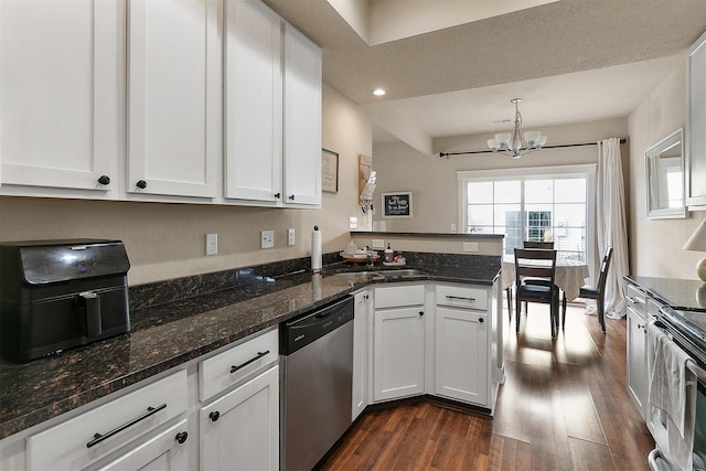 kitchen with appliances with stainless steel finishes, white cabinetry, an inviting chandelier, hanging light fixtures, and kitchen peninsula