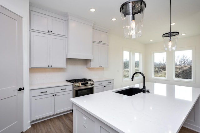 kitchen with hanging light fixtures, sink, white cabinets, and stainless steel gas range