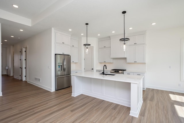 kitchen with pendant lighting, white cabinetry, appliances with stainless steel finishes, and an island with sink