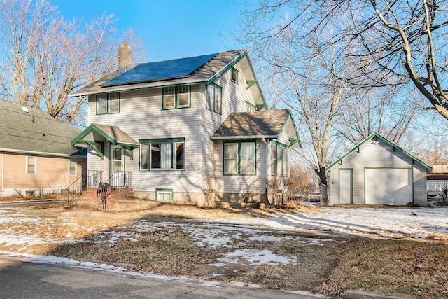 view of front of property with a garage, solar panels, and an outdoor structure