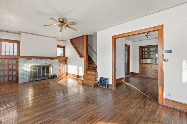 unfurnished living room featuring a brick fireplace, dark hardwood / wood-style floors, and ceiling fan