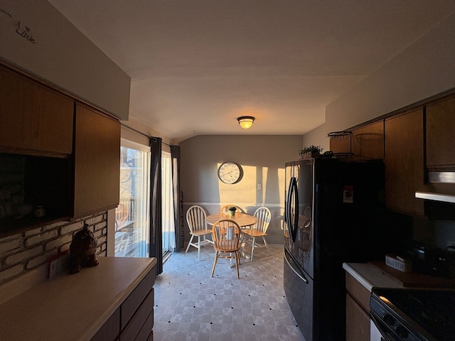 kitchen with black refrigerator with ice dispenser, range with electric stovetop, and vaulted ceiling