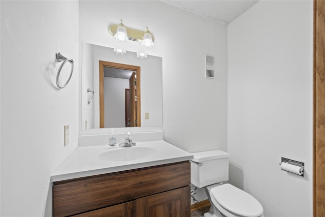 bathroom with a textured ceiling, toilet, and vanity