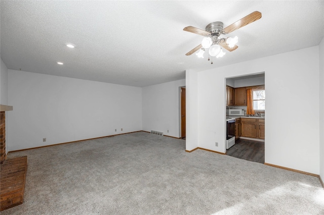 unfurnished living room with a textured ceiling, ceiling fan, and dark carpet