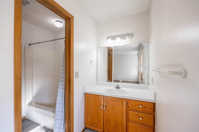 bathroom with a textured ceiling, shower / bathtub combination with curtain, and vanity