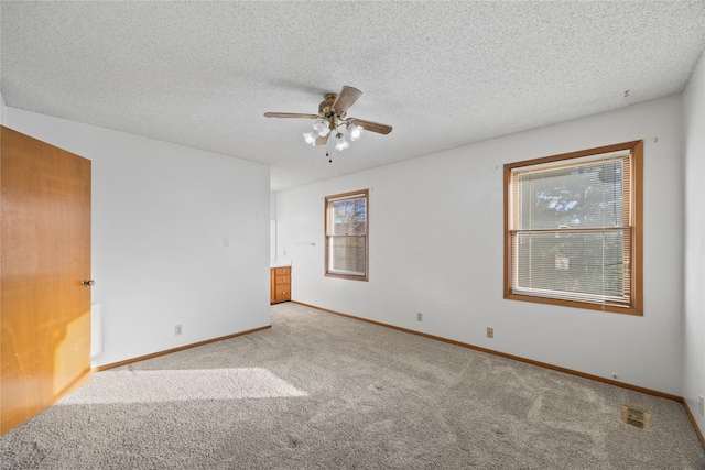 spare room with light carpet, ceiling fan, and a textured ceiling