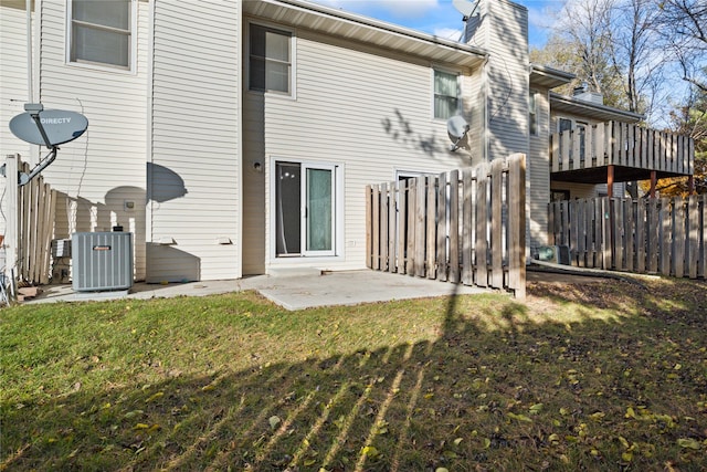 back of property with central AC unit, a lawn, and a patio