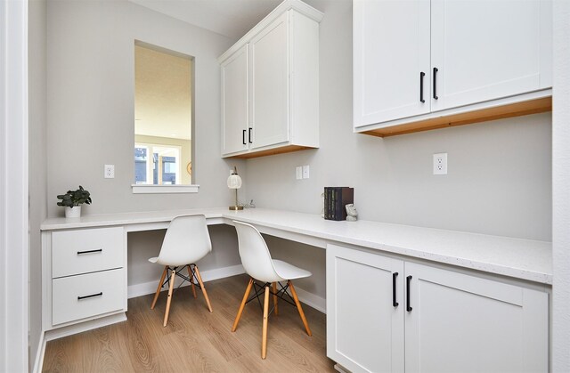 home office with light hardwood / wood-style flooring and built in desk