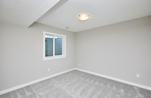 unfurnished room with carpet and a textured ceiling