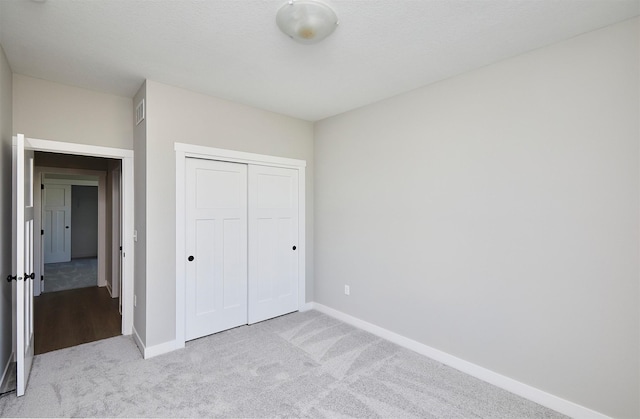 unfurnished bedroom with light carpet and a closet