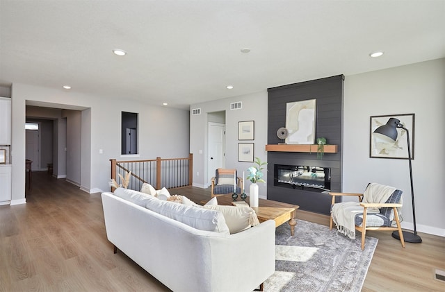 living room with a large fireplace and light wood-type flooring