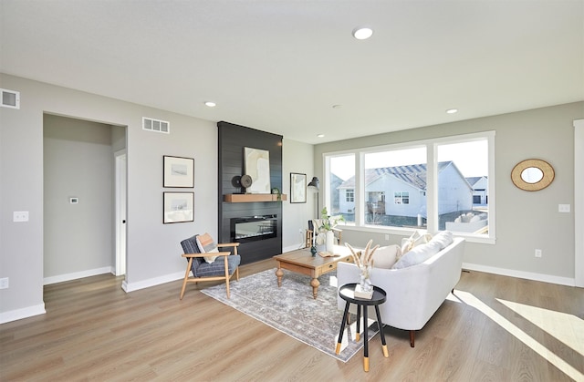 living room featuring a large fireplace and light wood-type flooring