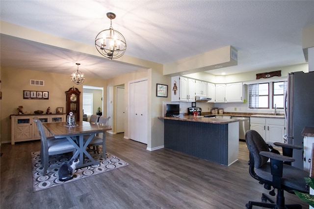 dining space with a textured ceiling, sink, dark hardwood / wood-style floors, and a notable chandelier