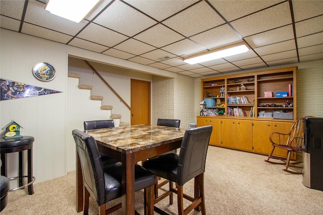 carpeted dining room featuring a drop ceiling