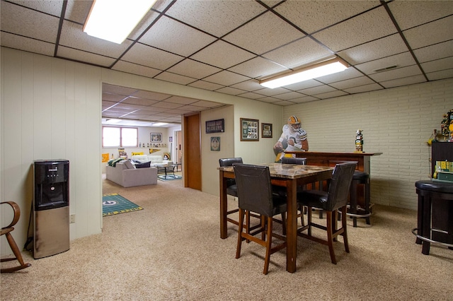 dining room with brick wall, carpet, and a paneled ceiling