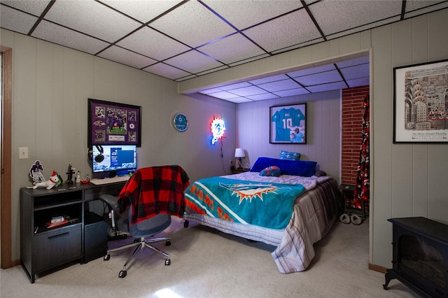 bedroom featuring a wood stove, a drop ceiling, and carpet flooring