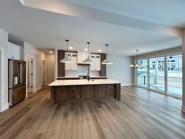 kitchen with light wood-style flooring, a notable chandelier, white cabinetry, high end fridge, and light countertops