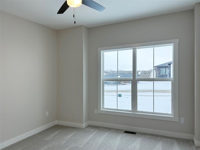 spare room featuring baseboards, visible vents, a ceiling fan, and light colored carpet