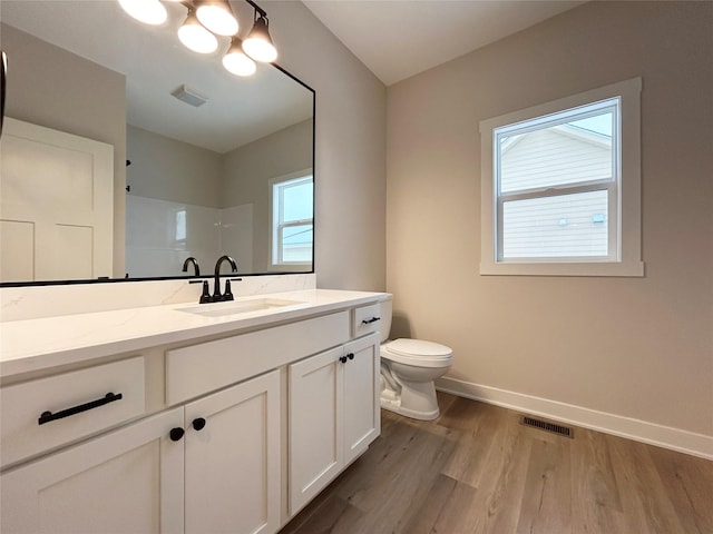 bathroom featuring visible vents, toilet, vanity, wood finished floors, and baseboards