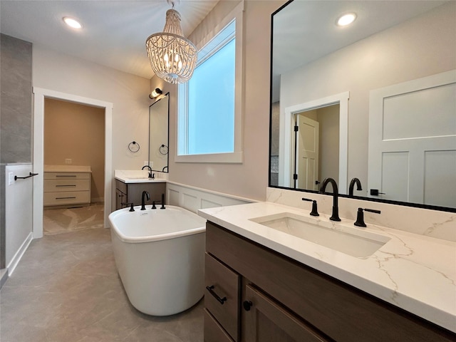 full bathroom with recessed lighting, a soaking tub, a sink, and an inviting chandelier