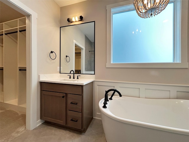 bathroom featuring a healthy amount of sunlight, a wainscoted wall, a freestanding bath, and vanity