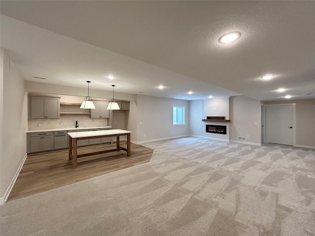 interior space featuring a glass covered fireplace, gray cabinets, visible vents, and baseboards