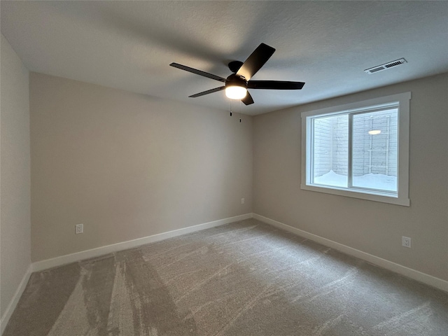 carpeted empty room with a textured ceiling, a ceiling fan, visible vents, and baseboards