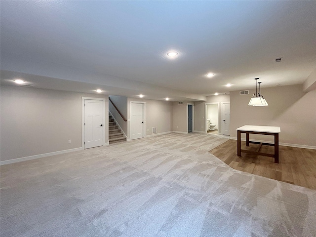 finished basement featuring light carpet, baseboards, stairs, and visible vents