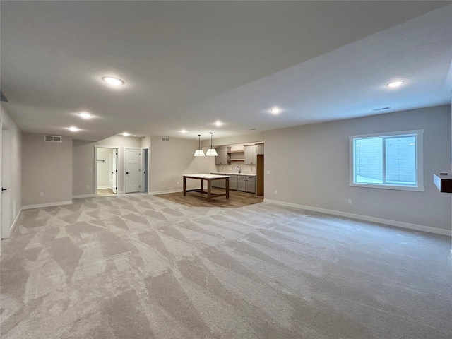 below grade area with light carpet, baseboards, visible vents, and recessed lighting