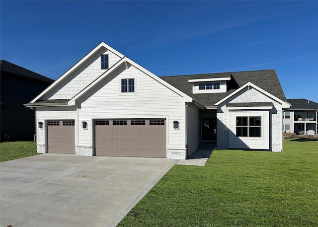 view of front facade with concrete driveway, a front lawn, an attached garage, and a shingled roof