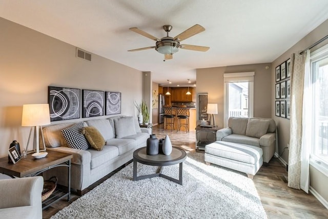 living room featuring ceiling fan, a healthy amount of sunlight, and wood-type flooring