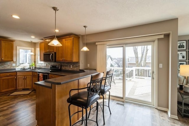 kitchen with kitchen peninsula, sink, hanging light fixtures, a breakfast bar area, and stainless steel appliances