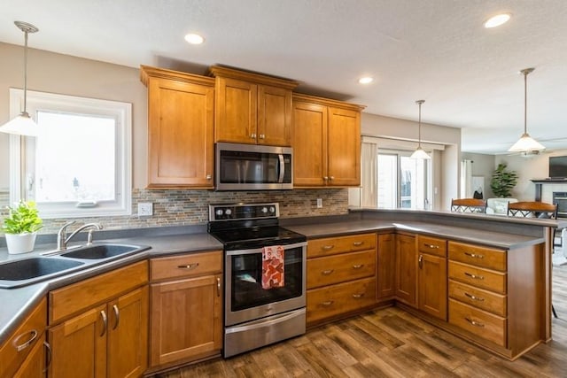 kitchen with backsplash, sink, stainless steel appliances, and pendant lighting