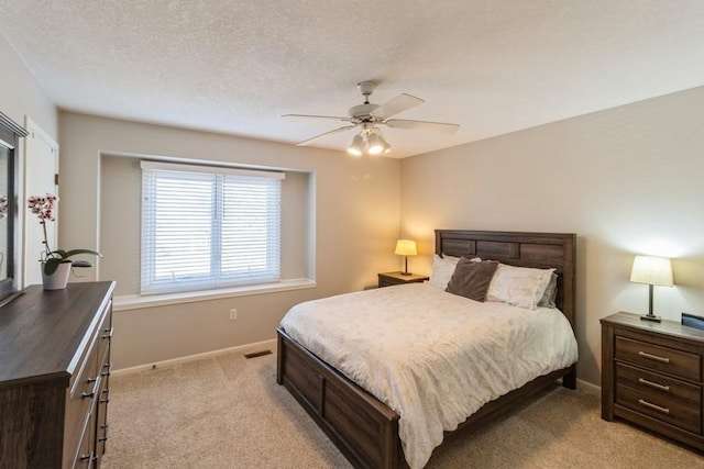 bedroom featuring a textured ceiling, ceiling fan, and light colored carpet