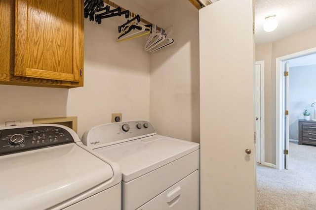 washroom featuring cabinets, light colored carpet, and washer and clothes dryer